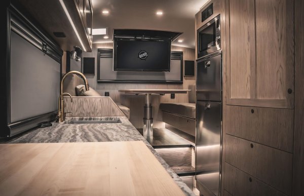 Елегантният интериор съчетава наситени дървесни тонове с покрития от неръждаема стомана. Отвореното разпределение включва трапезария, всекидневна и просторна кухня с индукционна печка с три котлона, хладилник с фризер, пералня и мивка в индустриален стил, както и много място за съхранение. Снабден е с два телевизора и климатик, RV не пести комфорт.
